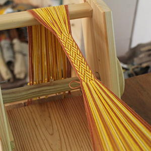 photo d'un métier à tisser artisanal en bois avec un galon en cours de tissage