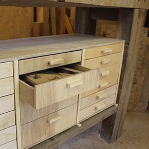 photo d'un meuble de rangement à tiroirs réalisé en bois, 
				sur mesure sous un établi