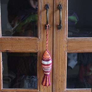 photo d'un poisson brodé accroché en déco à une armoire vitrée